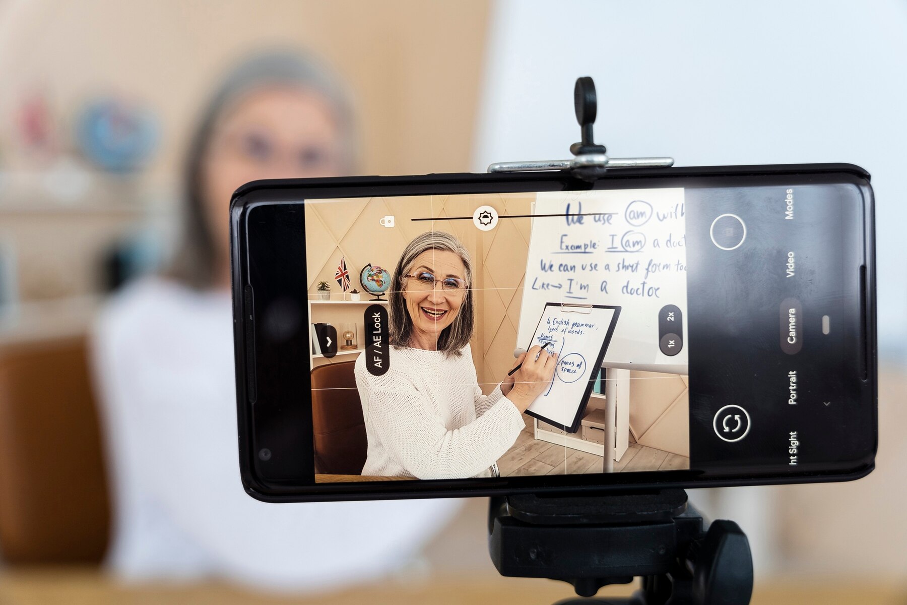 PEIRATS ACADÉMIA - Sobre nosotros - profesora ingles sonriente haciendo lecciones linea su telefono inteligente